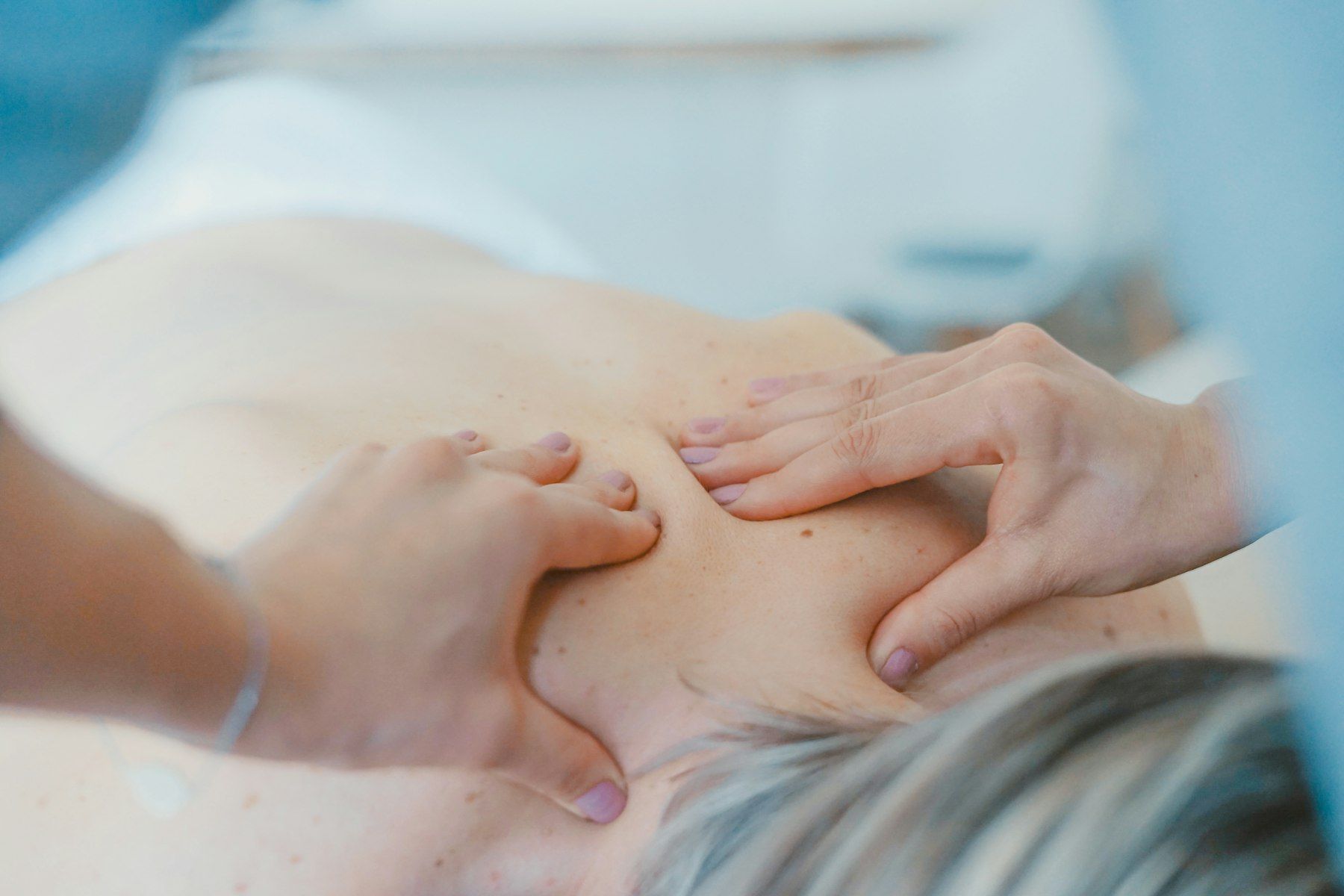 A massage therapist working on a client’s neck and shoulders